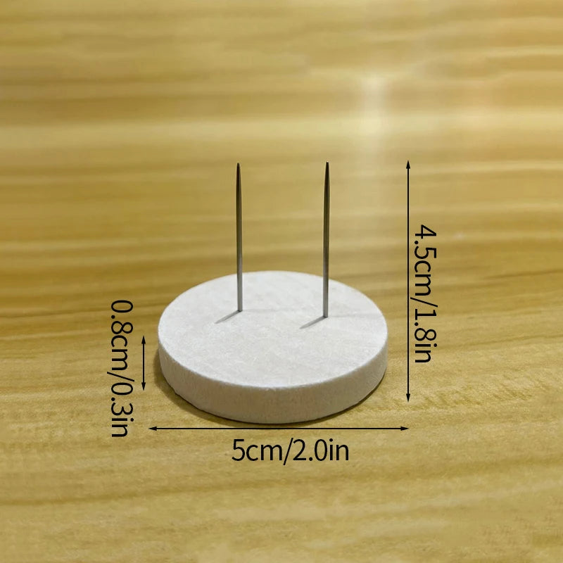 A white circular disc with two metal pins is shown on a wooden surface, illustrating its dimensions.