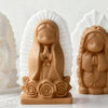 A terracotta silicone mold of a praying angel girl with hands clasped, set against a white background.