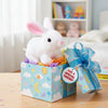 A white rabbit plush toy is sitting in a blue gift box decorated with clouds and stars.