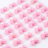 Pink acrylic bow beads scattered on a white background for jewelry making