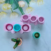 A pink silicone mold with multiple depressions is shown next to a small green succulent plant.