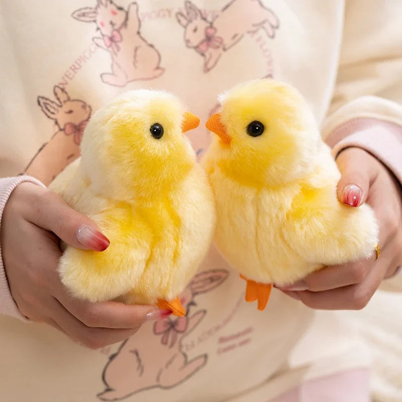 Two fluffy yellow chick plush toys being held by a person against a light-colored shirt.