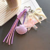 A set of beaded keychains featuring purple and pink strands, a seashell charm, and a star charm.