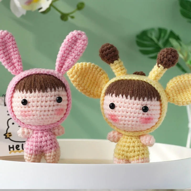 A pair of handmade crochet bunny dolls, one pink and one yellow, displayed against a green background.