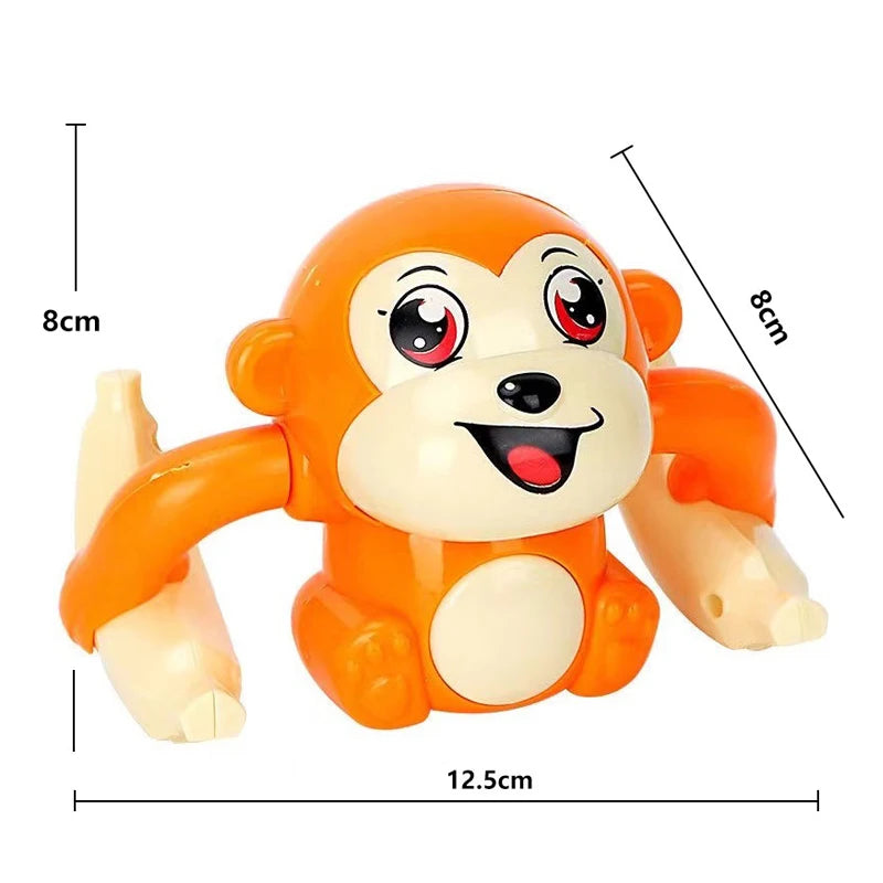 Jouet singe électrique orange roulant avec grands yeux et sourire, avec lignes de dimension.