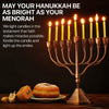 A brass candelabra holds multiple lit yellow taper candles, set against a dark background with a pastry.