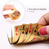 A hand holds a flexible, foldable deck of golden playing cards with red and black designs.