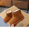 A pair of brown suede winter boots with faux fur lining are being held, resting on a cardboard box.