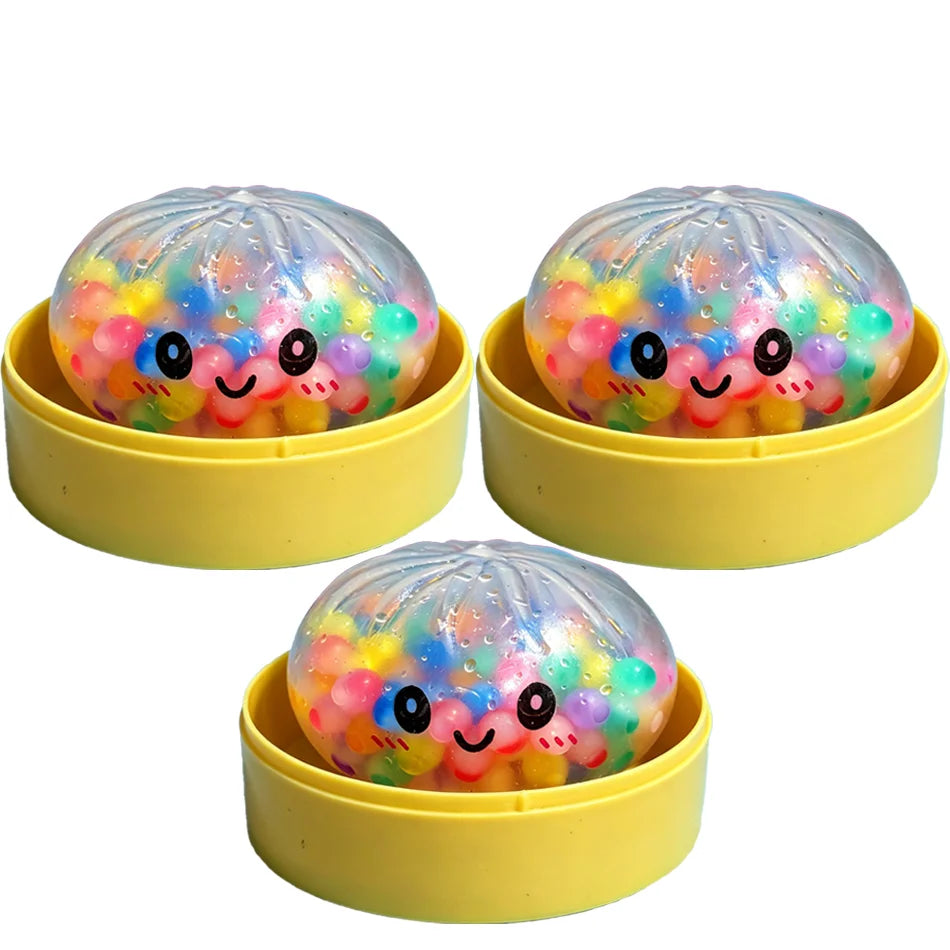 Three clear plastic glitter dumpling squishy stress relief toys in yellow containers