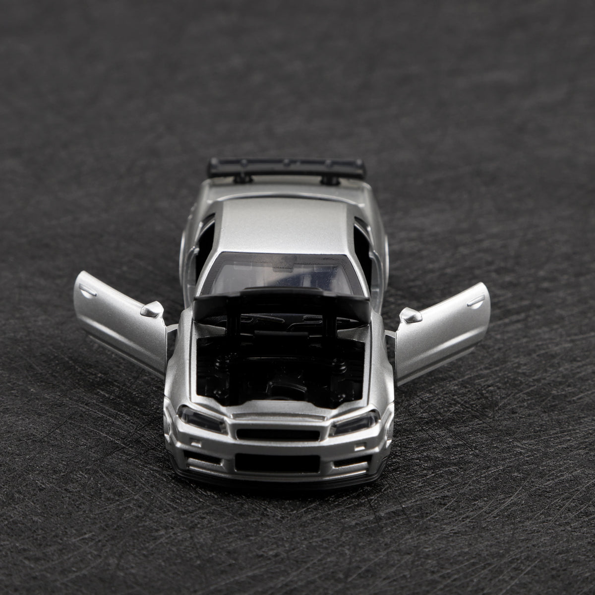 A silver 1/36 scale die-cast sports car with pull-back action displayed on a dark surface.