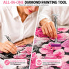 A hand applies diamonds to fabric using a diamond painting pen and roller tool.