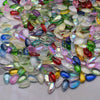 A close-up view of a pile of multicolored water drop Czech glass beads for jewelry making.