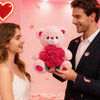 A smiling couple stands in a pink room, with the man holding an adorable pink plush bear with a large pink rose.