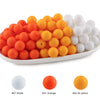 A collection of round silicone beads in white, orange, and yellow colors arranged in a line.