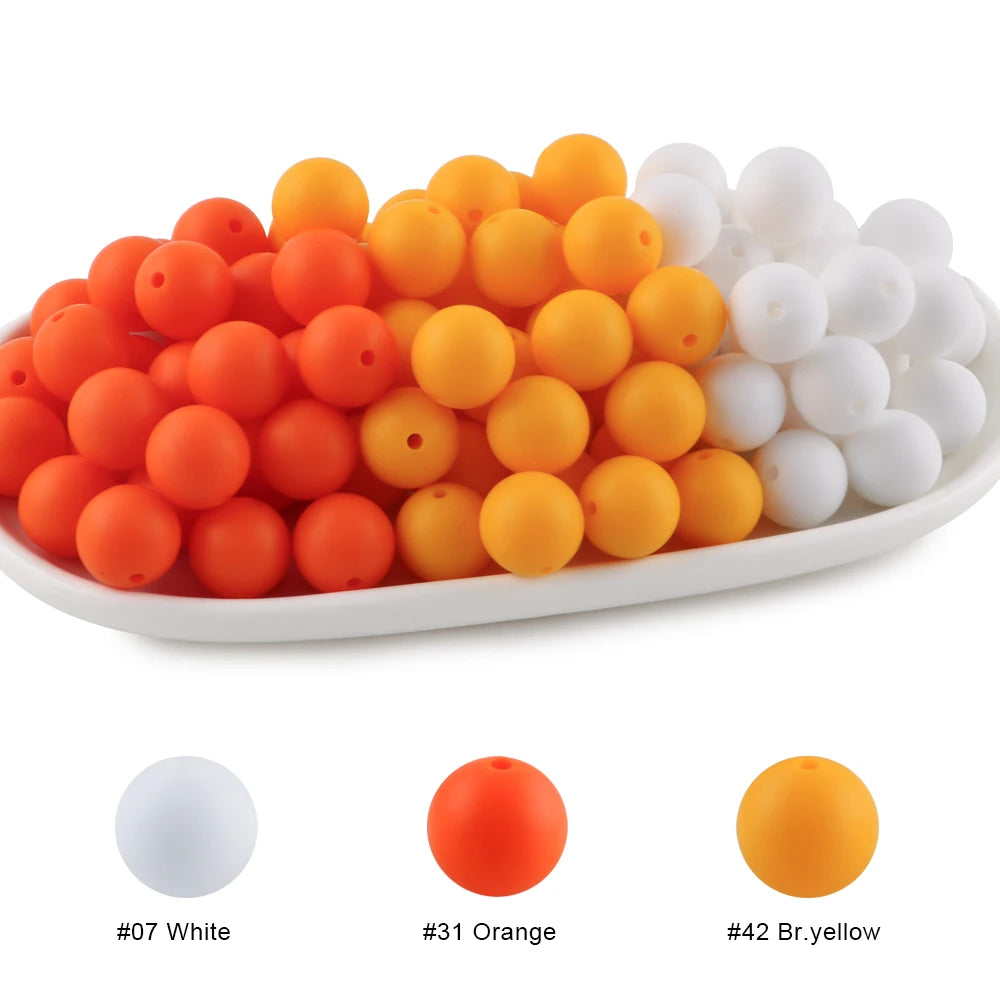 A collection of round silicone beads in white, orange, and yellow colors arranged in a line.