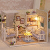 A detailed miniature dollhouse kit featuring white furniture, a cozy interior, and decorative elements for play.