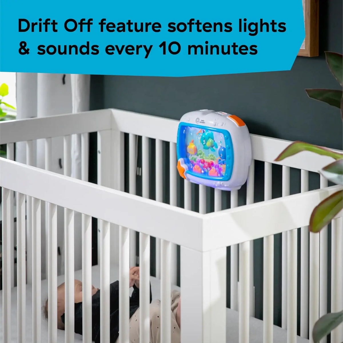 A white crib railing shows an ocean-themed soother device with lights and sounds.