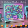 A glowing LED drawing board displaying colorful drawings of a rainbow, sun, rocket, and dinosaur on a white base.