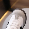 Close-up view of a white casual sneaker with light beige suede accents and black detailing.