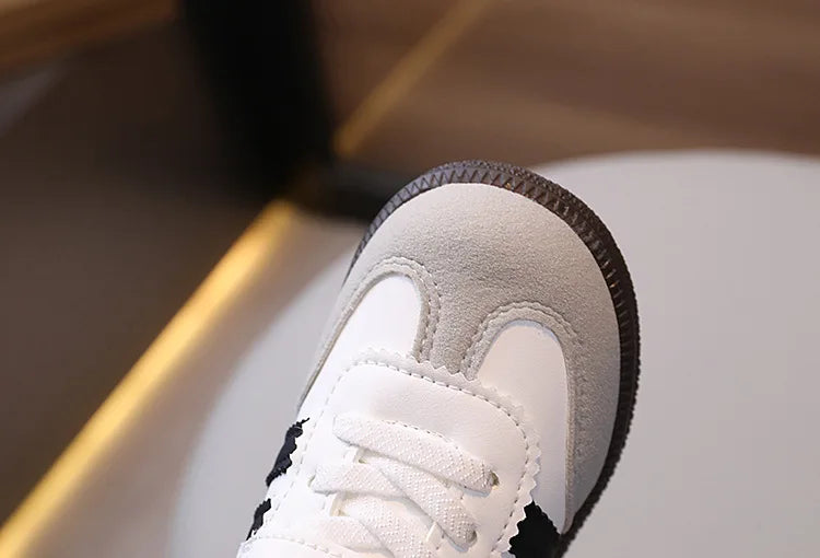 Close-up view of a white casual sneaker with light beige suede accents and black detailing.