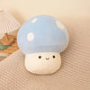 A light blue mushroom plush pillow with white spots rests on a beige textured fabric.