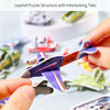 A hand holds a purple and white foam puzzle piece shaped like an airplane from a layered puzzle structure.
