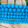 A hand holds a strand of bright blue, translucent cat eye stone beads for jewelry making.