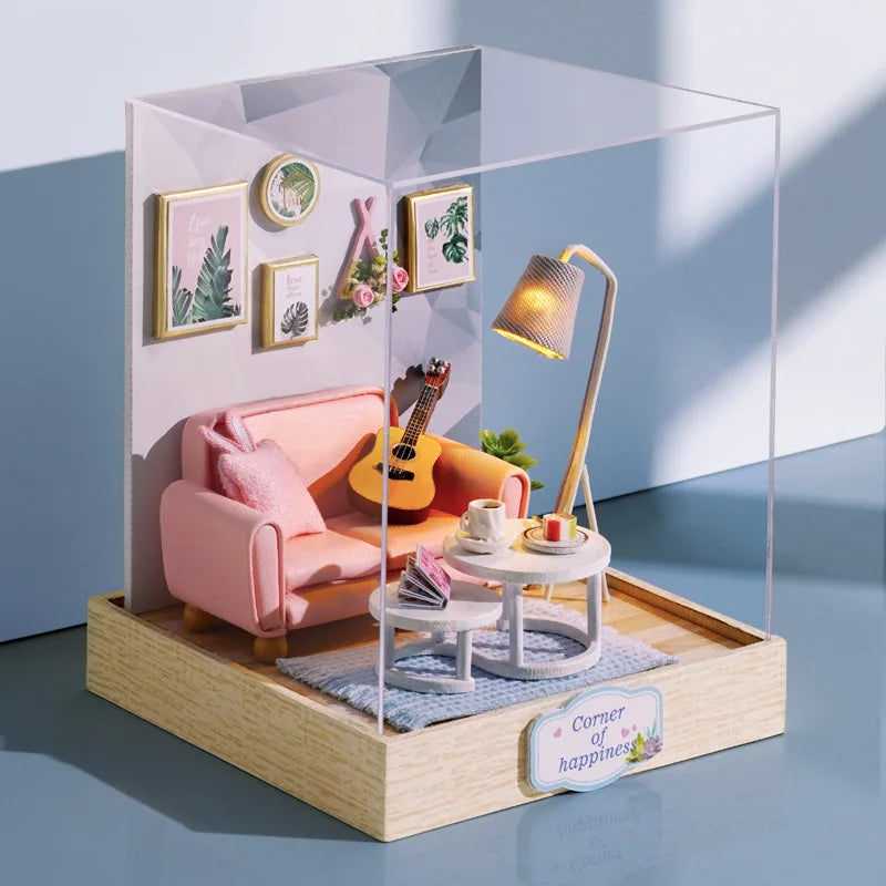 A clear acrylic display box featuring a miniature pink armchair, wooden decor, and a gold-colored lamp.
