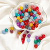 A bowl filled with colorful round glass beads in various shades of blue, pink, yellow, and red for DIY jewelry making