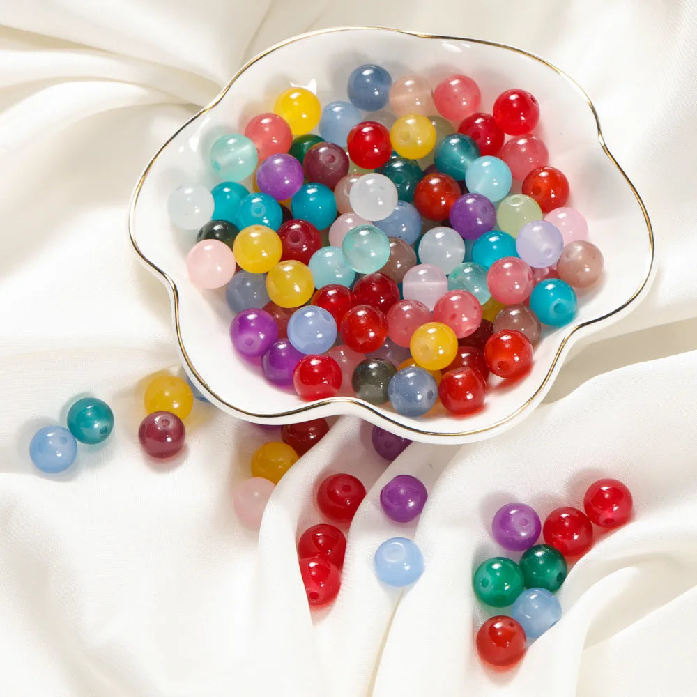 A bowl filled with colorful round glass beads in various shades of blue, pink, yellow, and red for DIY jewelry making