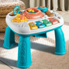 A white musical baby piano playmat with a light-up keyboard and various hanging toys sits on a light-colored rug.