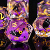 A close-up of a set of iridescent purple and gold liquid core dice used for tabletop gaming.