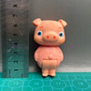 A small, pink cartoon figurine shaped like a pig, displayed next to a ruler.