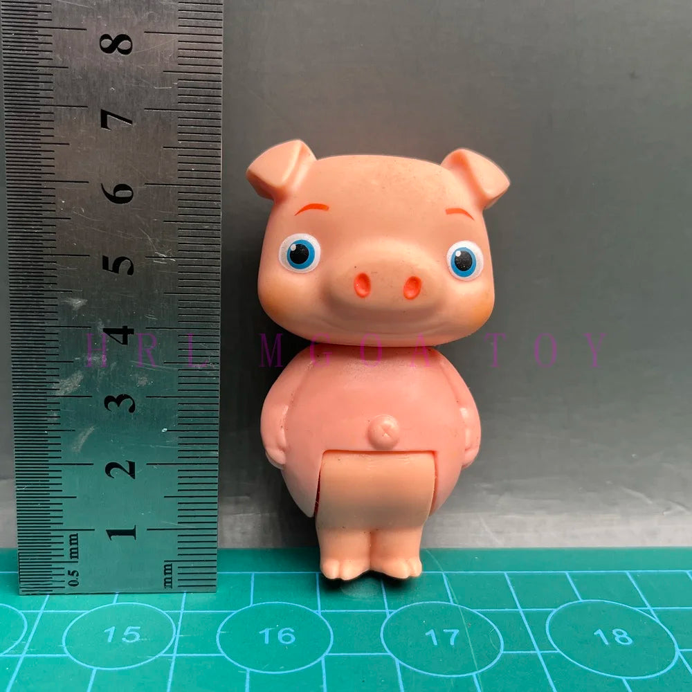 A small, pink cartoon figurine shaped like a pig, displayed next to a ruler.