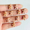 A hand displays a set of 30 Christmas gingerbread resin nail art charms featuring orange and white colors.