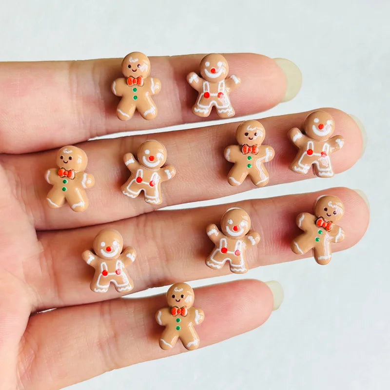 A hand displays a set of 30 Christmas gingerbread resin nail art charms featuring orange and white colors.