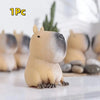 A small, light beige and gray squishy toy shaped like a capybara, resting on a white surface.