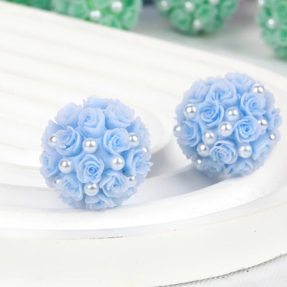 Light blue rose flower ball acrylic beads with pearl accents arranged on a white surface.
