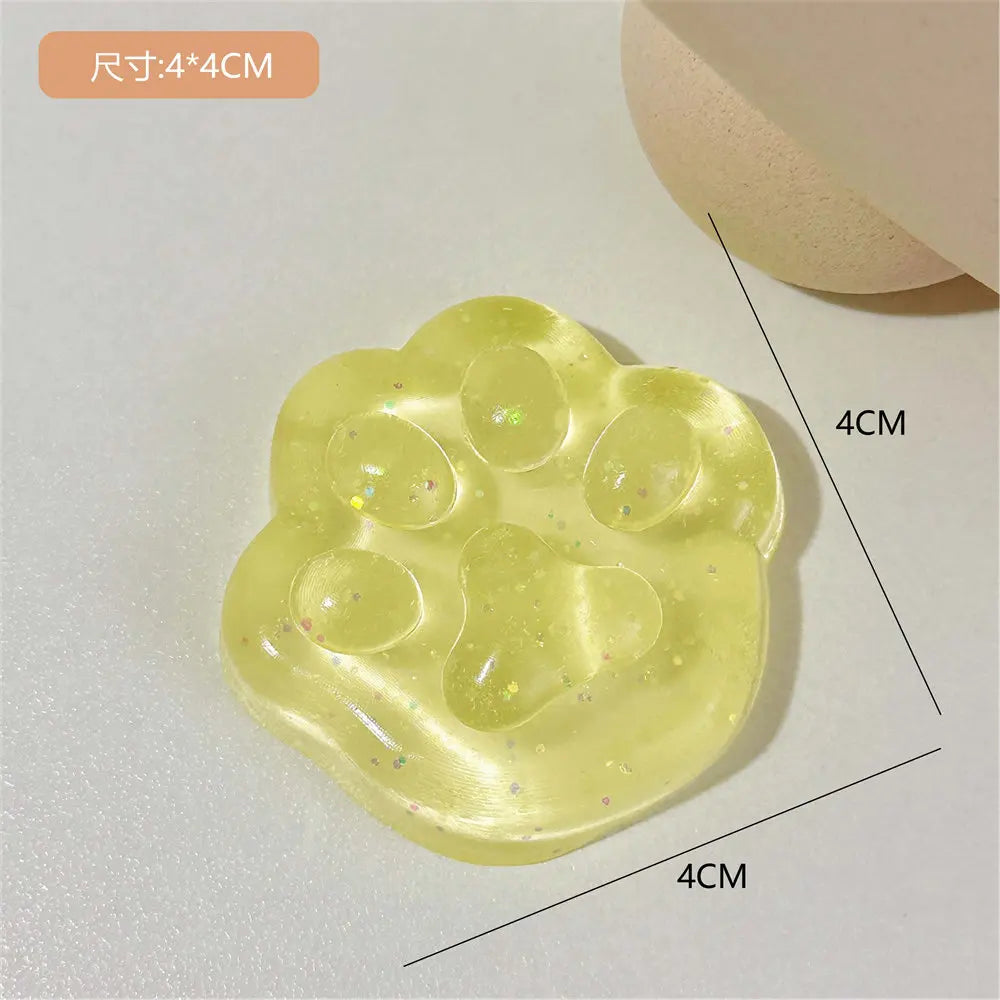 A yellow squishy toy shaped like a cat paw, featuring multiple soft jelly pads and glitter accents.