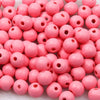 A pile of small, round pink wooden beads for jewelry making and DIY crafts.