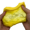 A hand is squeezing a bright yellow, squishy cheese ball stress relief toy.