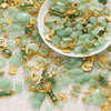 A pile of light green imitation jade charms and gold-colored jewelry components for crafting.