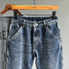 A pair of vintage loose fit denim harem jeans hanging on a wooden hanger.