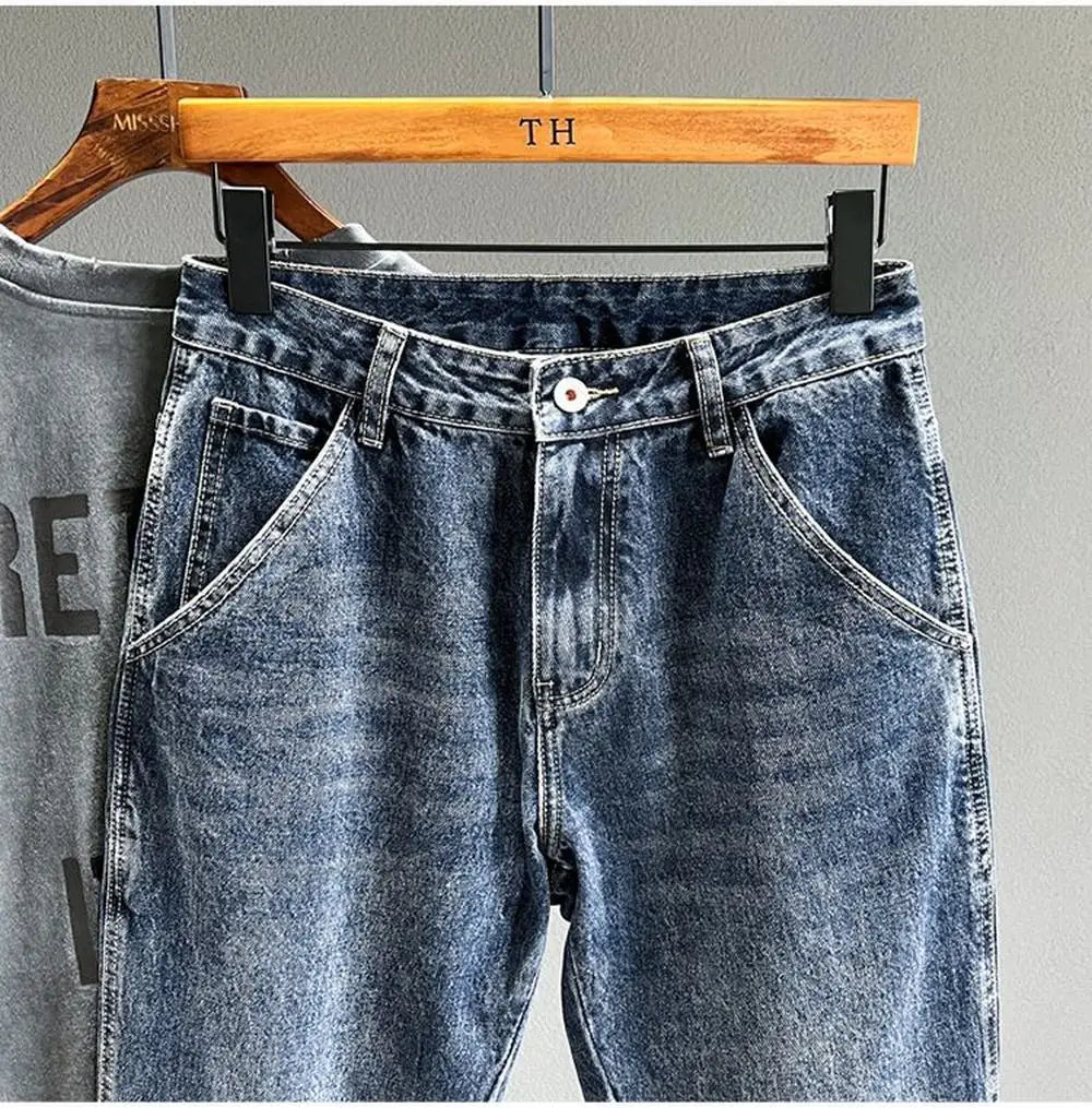 A pair of vintage loose fit denim harem jeans hanging on a wooden hanger.