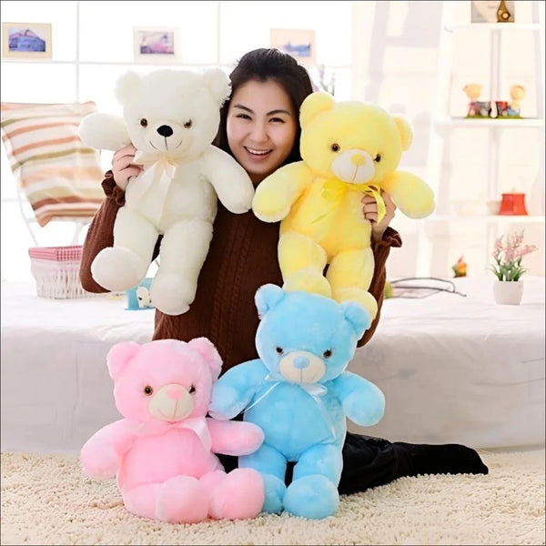 A woman is holding several plush teddy bears in various colors including white yellow and pink against a bright background.