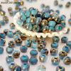A pile of vibrant round blue and gold beads for jewelry making scattered on a white surface.