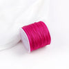 A roll of bright magenta pink macrame cord for jewelry making and crafts.