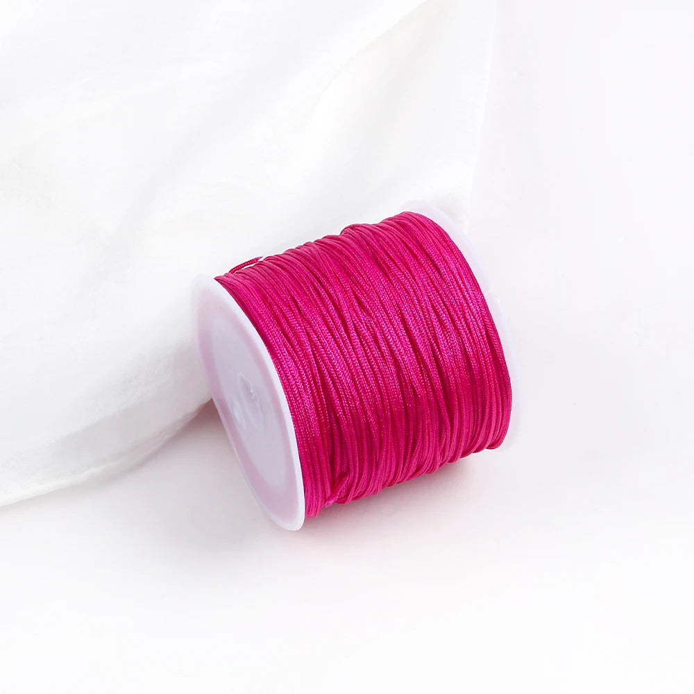 A roll of bright magenta pink macrame cord for jewelry making and crafts.
