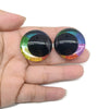 Pair of glitter cartoon safety eyes with black and iridescent colored lenses held in a hand