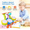 A toddler plays with an interactive drum set featuring light-up pads, a microphone, and various colorful wooden instruments.